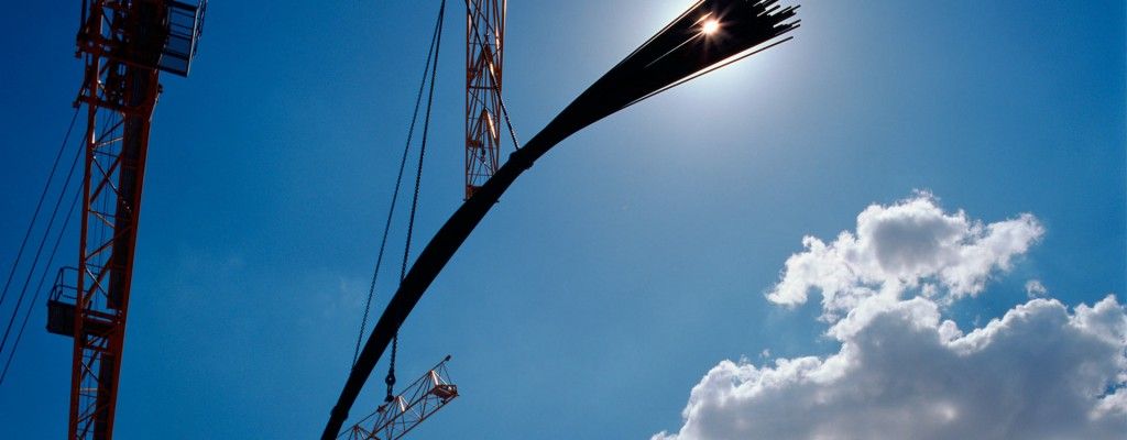 grua en obra sobre cielo azul con nueves blancas